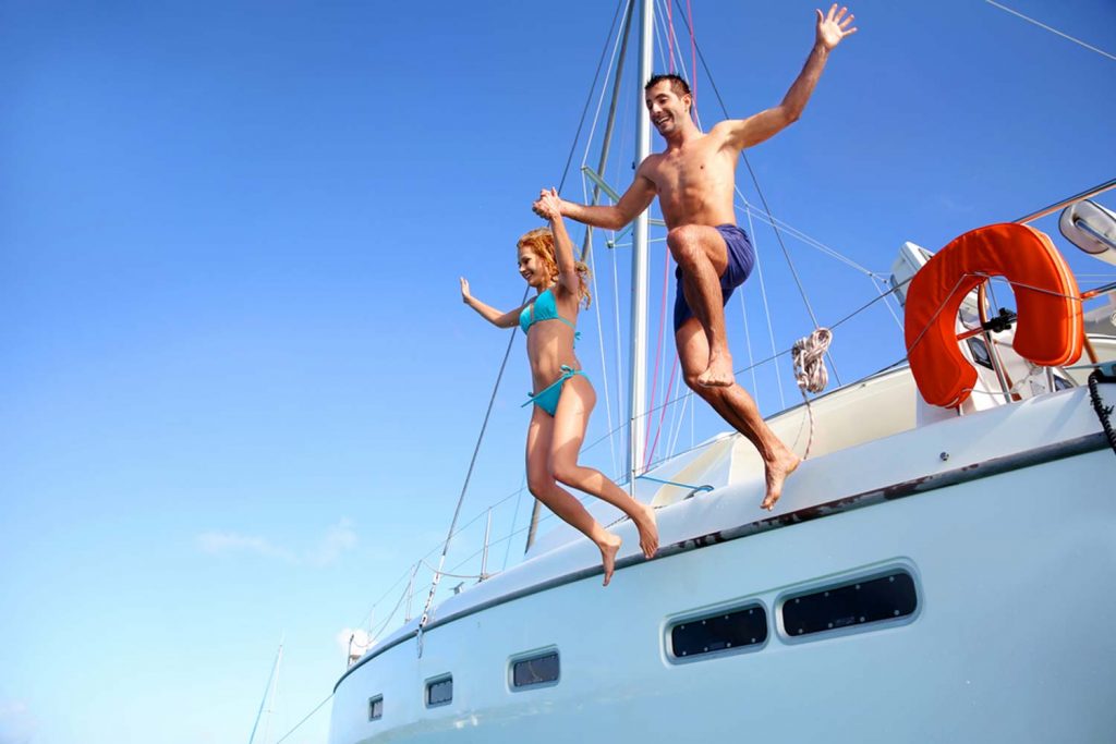 Ein junges Paar springt von einer Yacht ins Meer