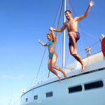 Ein junges Paar springt von einer Yacht ins Meer