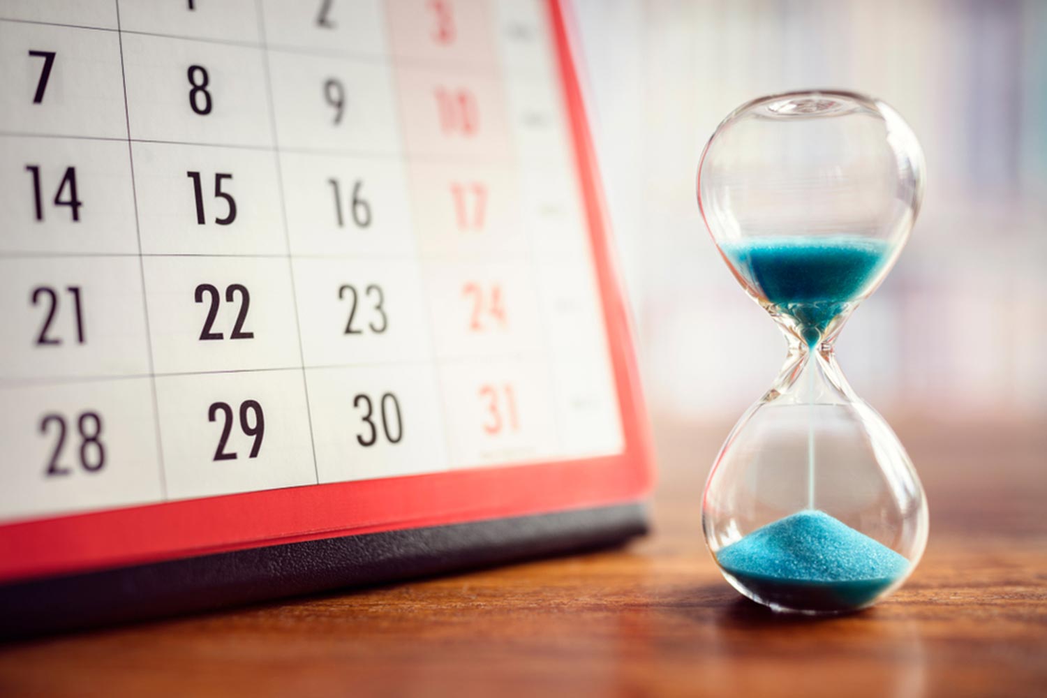 Sanduhr läuft neben einem Kalender ab
