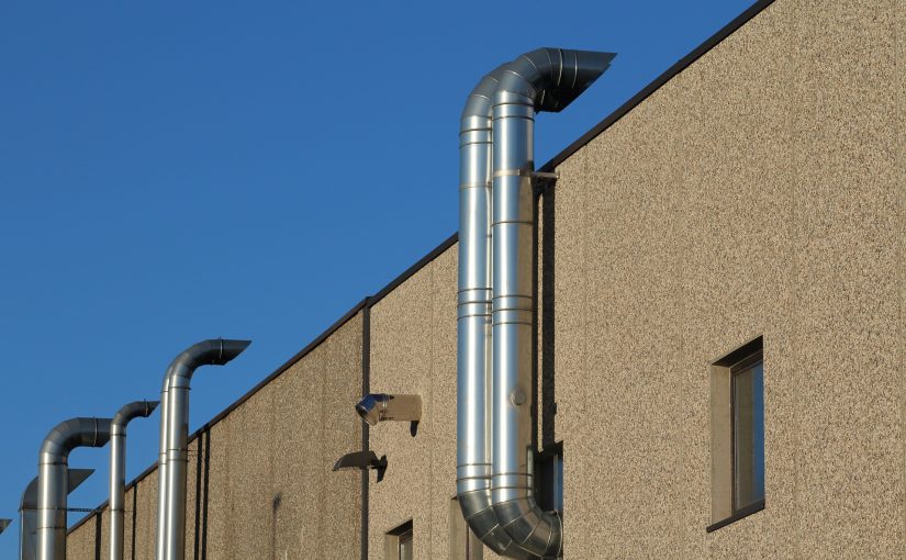 Silberne Rohre an einem Gebäude mit Fenstern